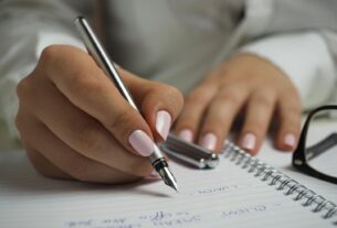 A detailed image of handwriting in a notebook with a fountain pen and glasses, ideal for office themes.